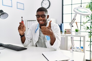 Young african american doctor man holding electronic cigarette at medical clinic smiling happy and...
