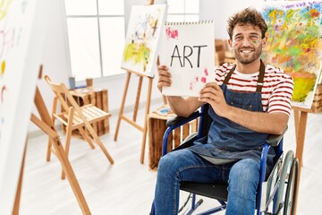 Young hispanic man sitting on wheelchair holding art notebook at art studio