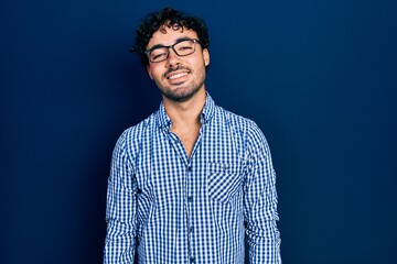 Fototapeta premium Young hispanic man wearing casual clothes and glasses with a happy and cool smile on face. lucky person.