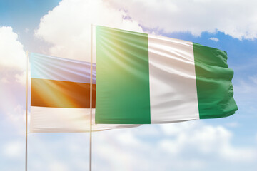 Sunny blue sky and flags of nigeria and estonia