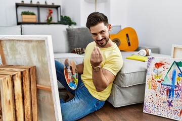 Young man with beard painting canvas at home doing money gesture with hands, asking for salary...