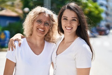 Two women mother and daughter hugging each other at street