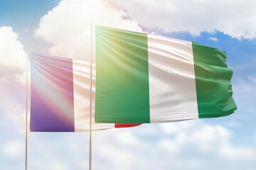 Sunny blue sky and flags of nigeria and france