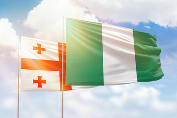 Sunny blue sky and flags of nigeria and georgia