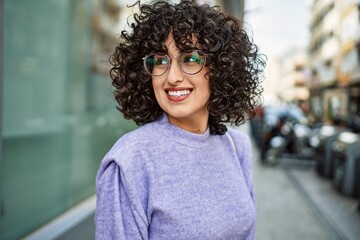 Fototapeta na wymiar Young middle east woman smiling confident wearing glasses at street