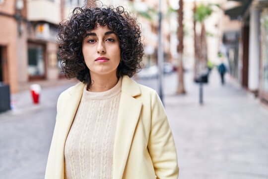 Young middle east woman executive standing with serious expression at street