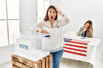 Young brunette woman voting putting envelop in ballot box stressed and frustrated with hand on...