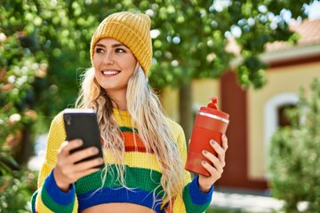 Young blonde woman using smartphone at the park