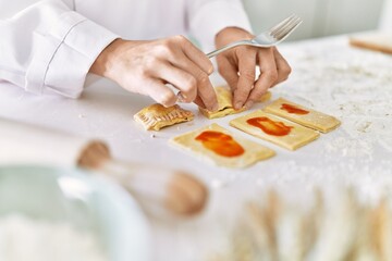Young woman wearing cook uniform cooking pasta at kitchen