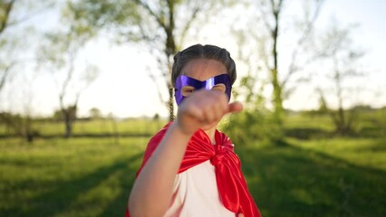 Girl in red superhero cape play in park. Family happiness. Child dream of becoming champion. Strong will to win.Girl in superhero mask on summer vacation. Child plays in park. Happy family concept
