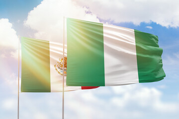 Sunny blue sky and flags of nigeria and mexico