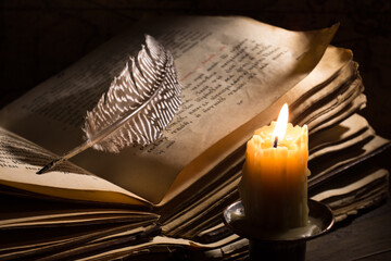 Lighting candle near a medieval book. Vintage still life with open old book