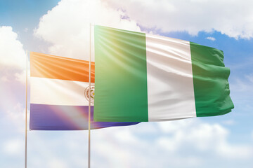 Sunny blue sky and flags of nigeria and paraguay