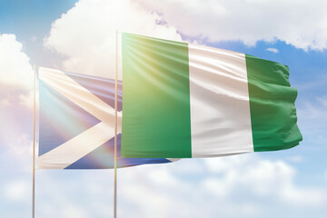 Sunny blue sky and flags of nigeria and scotland