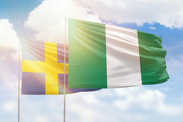 Sunny blue sky and flags of nigeria and sweden