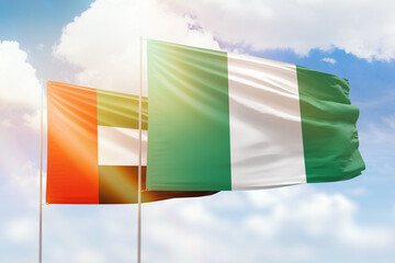 Sunny blue sky and flags of nigeria and uae