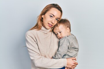 Young caucasian woman holding and hugging her son with love. Family of two bonding together. Mother holding infant toddler