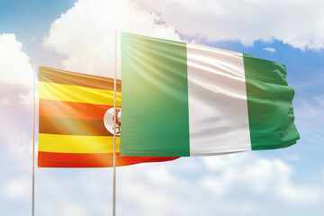 Sunny blue sky and flags of nigeria and uganda