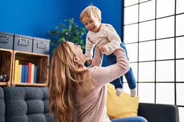 Mother and son holding kid on air sitting on sofa at home