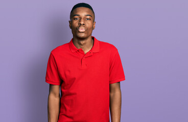 Young african american man wearing casual red t shirt looking at the camera blowing a kiss on air being lovely and sexy. love expression.
