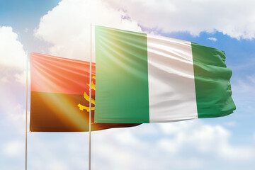 Sunny blue sky and flags of nigeria and angola