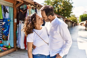 Naklejka premium Middle age hispanic couple kissing and hugging at the city.