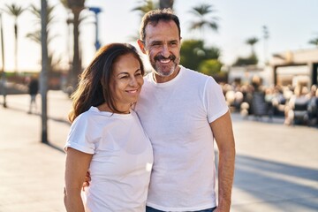 Obraz premium Middle age man and woman couple hugging each other standing at street