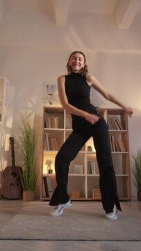 Influencer lifestyle. Viral content. Social media blogger. Overjoyed funny woman recording silly cute funky dance for vlog at home living room vertical.