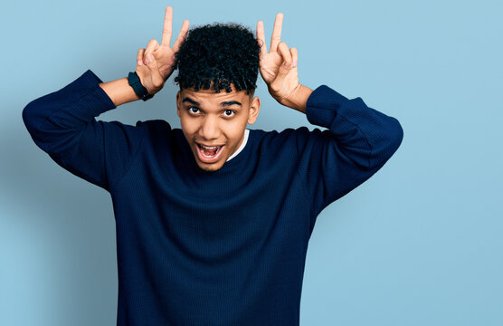 Young african american man wearing casual clothes posing funny and crazy with fingers on head as bunny ears, smiling cheerful