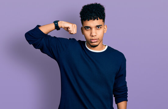 Young african american man wearing casual clothes strong person showing arm muscle, confident and proud of power