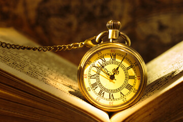 Vintage pocket watch with old book on a map background