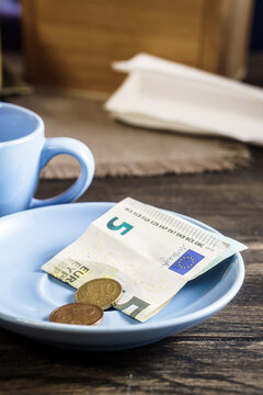Restaurant tips or gratuity, euro banknotes and coins on plate