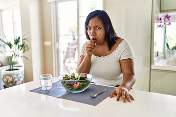 Obraz na płótnie Canvas Young hispanic woman eating healthy salad at home feeling unwell and coughing as symptom for cold or bronchitis. health care concept.