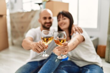 Young hispanic couple smiling happy toasting with champagne at new home.