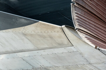 Close up on matte-finish metal panels on the fuselage of an aircraft. Part of jet exhaust also visible.  Suitable for background for graphics and text