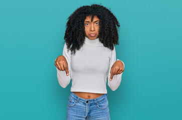 Young african american girl wearing casual clothes pointing down looking sad and upset, indicating...