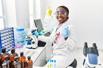 African woman working at scientist laboratory pointing finger to one self smiling happy and proud