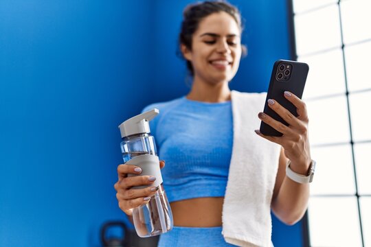 Young latin woman smiling confident using smartphone at sport center