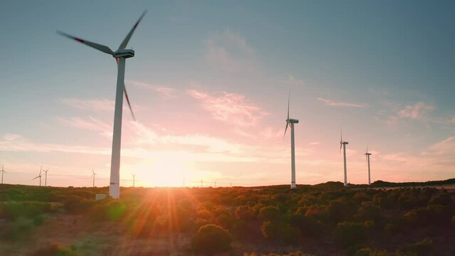 At sunset wind turbines in wind farm generating green energy. Beautiful amazing view in field. Ecology. Power station. Windmill.Close up