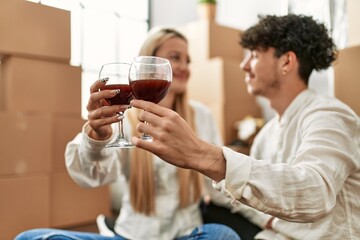Young beautiful couple smiling happy toasting with red wine at new home