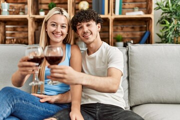 Young couple smiling happy toasting with red wine glass at home.