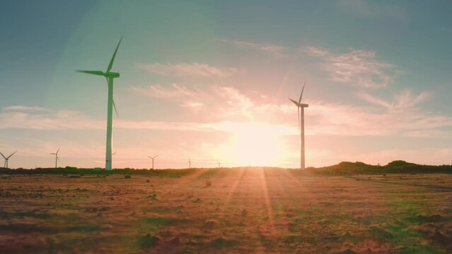 At sunset wind turbines in field wind farm generating green energy. Silhouettes windmills. Alternative energy. Ecology