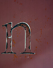 The small letter n isolated on side of rusty metal shipping container with red  burgundy or rust...