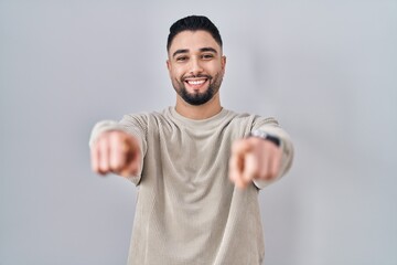 Young handsome man standing over isolated background pointing to you and the camera with fingers, smiling positive and cheerful