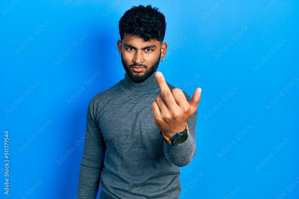 Poster Arab man with beard wearing turtleneck sweater showing middle finger, impolite and rude fuck off expression