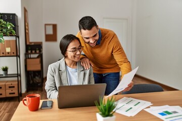 Two business workers smiling happy working sitting on desk at the office.