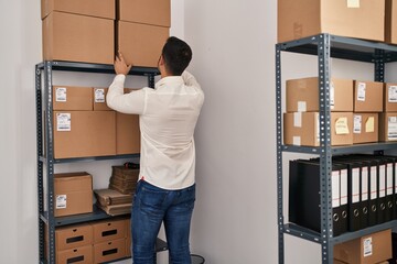 Young hispanic man e-commerce business worker organize packages at office