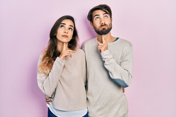 Young hispanic couple wearing casual clothes thinking concentrated about doubt with finger on chin...