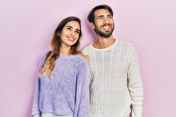 Young hispanic couple wearing casual clothes looking away to side with smile on face, natural expression. laughing confident.