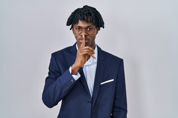 Young african man with dreadlocks wearing business jacket over white background asking to be quiet...